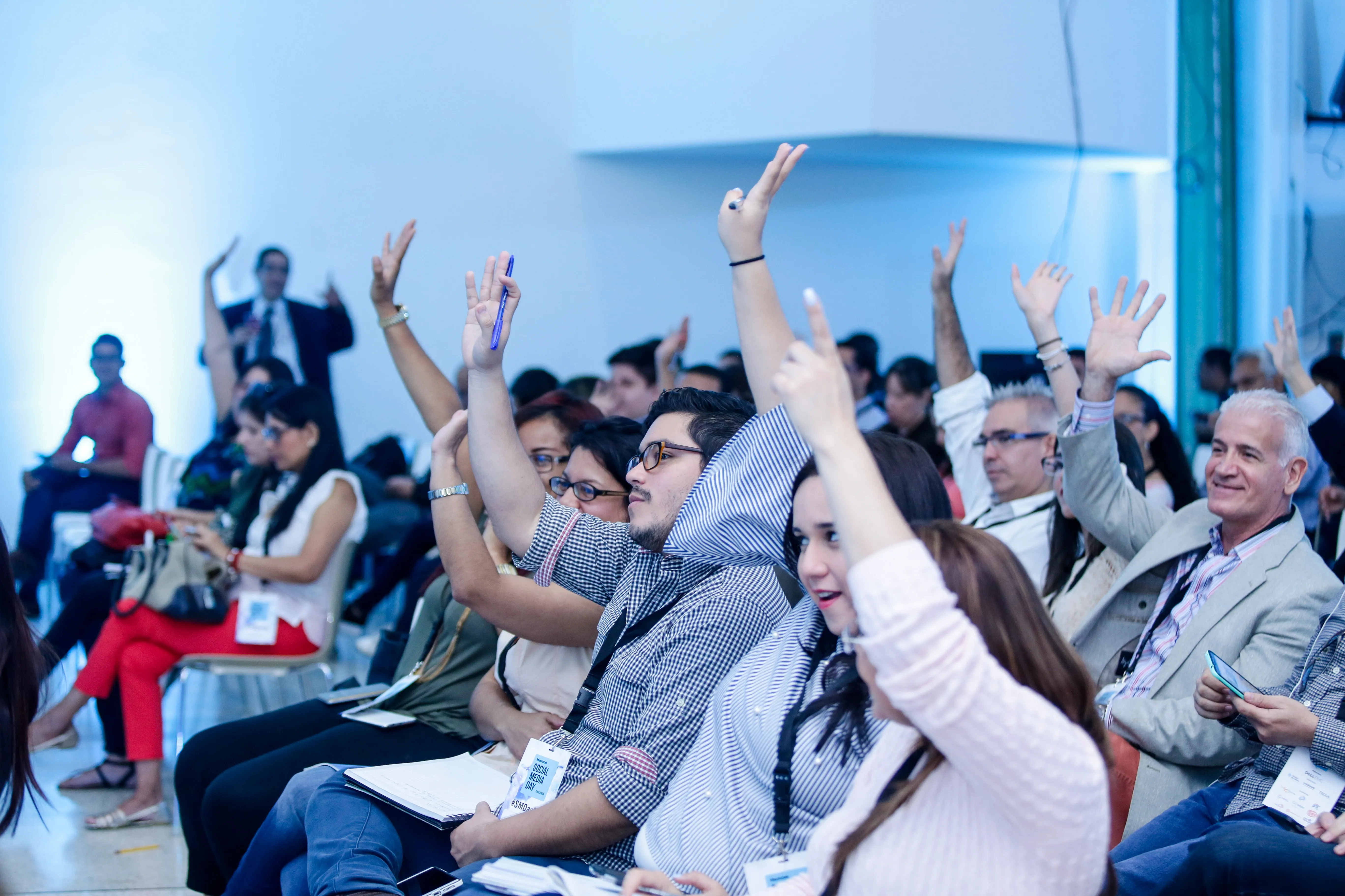 Grupo de asistentes a una charla levanta la mano en medio de ella