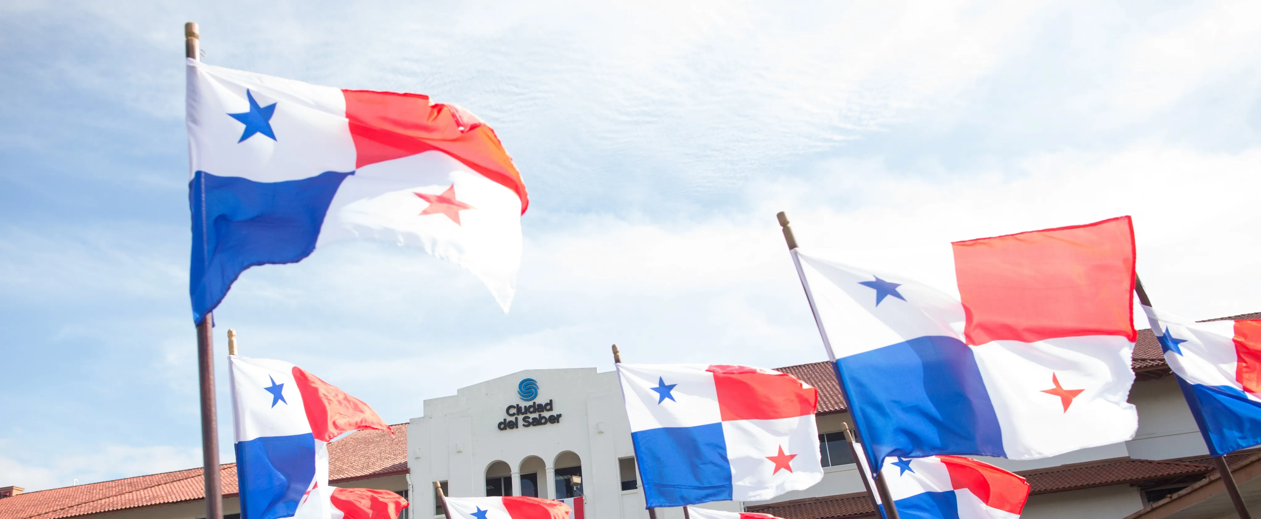 Banderas de Panamá y al fondo el edificio de Ciudad del Saber